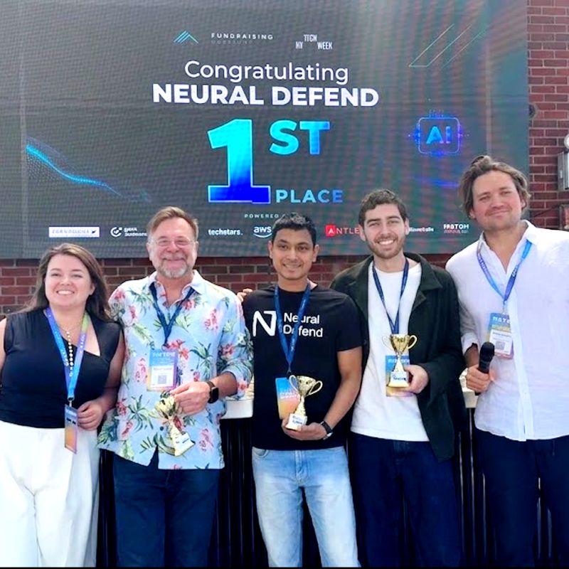 Piyush Verma holding the first-place trophy with organizers and another winning founder